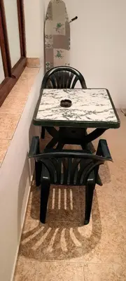 a table and a black chair with a table and a bench at Family House Victoria' Garden in Primorsko