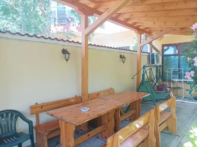 a wooden pergola with a wooden table on a patio at Family House Victoria' Garden in Primorsko