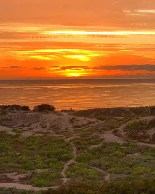 a sunset over the ocean with a dirt road at Family House Victoria' Garden in Primorsko