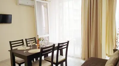 a dining room with a table and chairs and a window at Апартамент в непосредствена близост до плажа III in Burgas City