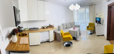 a kitchen and living room with yellow chairs and a table at Grand Villa Perle in Sveti Vlas
