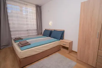 a bedroom with a bed with blue pillows and a window at Spacious 2BD Apartment - Walk to City Center and free Parking by Flat Mаnager in Burgas City