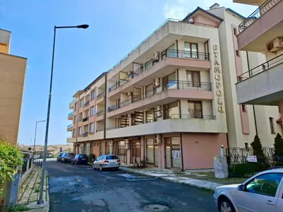 a tall building with cars parked in front of it at Stamopolu Apartments in Primorsko