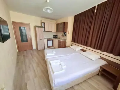 a bedroom with a large white bed and a kitchen at Stamopolu Apartments in Primorsko