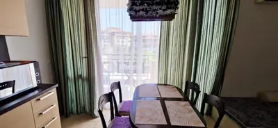 a dining table and chairs in a room with a window at Apartment in complex Sirena! in Sveti Vlas