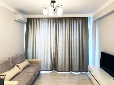 a living room with a couch and a television at APART-HOTEL Stamopolu Lux с изглед към морето in Primorsko