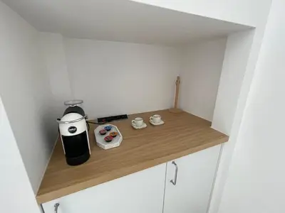 a small kitchen with a coffee maker on a wooden shelf at Flores Garden Pool & Sea View Studio in Chernomorets