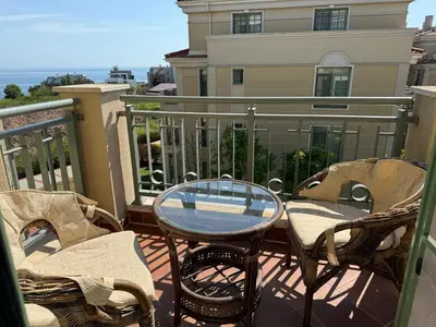 a patio with chairs and a glass table on a balcony at Flores Garden Pool & Sea View Studio in Chernomorets