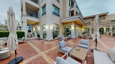a courtyard in a building with chairs and umbrellas at Flores Garden Pool & Sea View Studio in Chernomorets