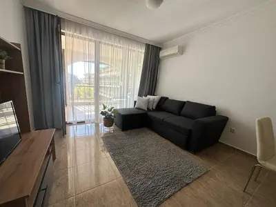 a living room with a black couch and a large window at Apartment in the complex Olymp in Sveti Vlas
