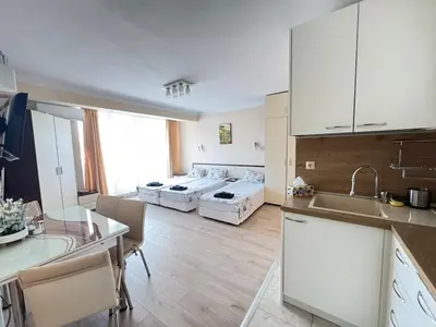 a kitchen with white cabinets and a living room with beds at Pomorian Pearl in Pomorie