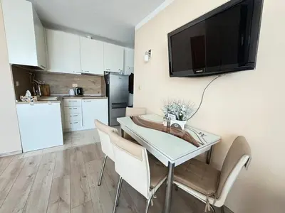 a kitchen with a table with chairs and a television on the wall at Pomorian Pearl in Pomorie