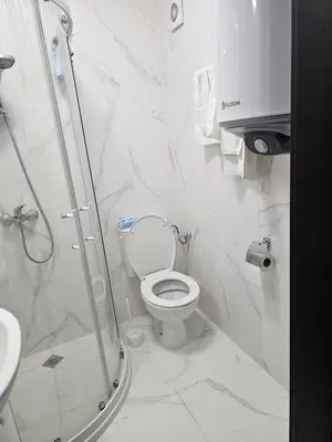 a white bathroom with a shower and a toilet at 3 комнатные новые апартаменты у моря in Sveti Vlas