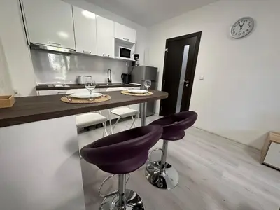 a kitchen with two bar stools and a clock on the wall at Apartment in Sveti Vlas in Sveti Vlas