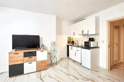 a kitchen with white cabinets and a flat screen tv at АПАРТАМЕНТИ Радина in Pomorie