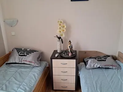 a bedroom with two beds and a table with a vase of flowers at Apartament in Aheloy in Aheloy