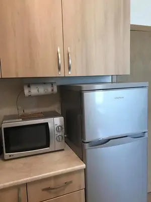 a kitchen with a microwave and a refrigerator at Тристаен апартамент в затворен комплекс in Chernomorets