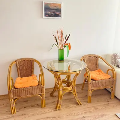 a glass table with two chairs and a vase with flowers at Тристаен апартамент в затворен комплекс in Chernomorets