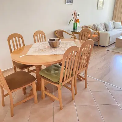 a dining room with a wooden table and chairs at Тристаен апартамент в затворен комплекс in Chernomorets