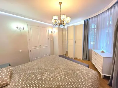 a bedroom with a bed and a dresser and a chandelier at Seaside Apartment in Varna City