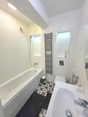 a white bathroom with a tub and a sink at Seaside Apartment in Varna City