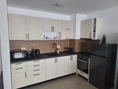 a kitchen with white cabinets and a black refrigerator at Sun Coast by the Sea in Sveti Vlas