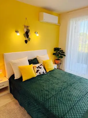 a bedroom with a green bed with yellow pillows at Апартаменти Sozopol Residence in Sozopol
