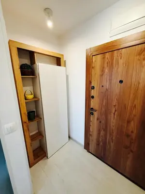 a room with a white refrigerator and a wooden door at Апартаменти Sozopol Residence in Sozopol