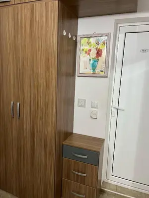 a bathroom with a wooden cabinet and a vase on the wall at Къща за гости Ками in Byala