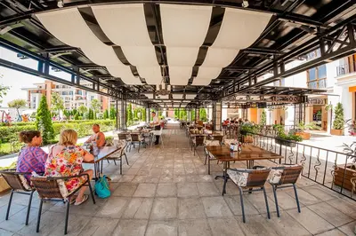 a group of people sitting at tables on a patio at Private Apartment 171 in Prestige Fort Beach Hotel in Sveti Vlas