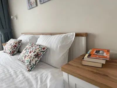 a bed with two pillows and a table with books at Smile Old City Apartment with Free parking and Sea view in Varna City
