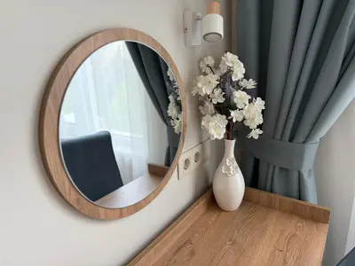 a round mirror on a wall with a vase with flowers at Smile Old City Apartment with Free parking and Sea view in Varna City