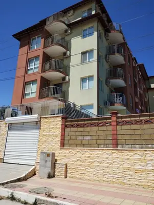 a tall building with balconies on top of a brick wall at Kasndra in Byala