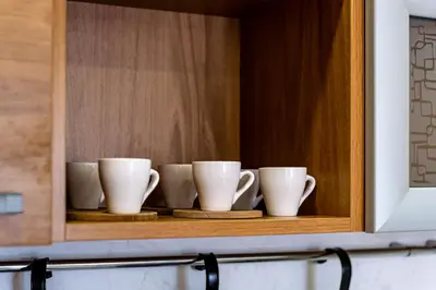 a cupboard with four coffee cups on a shelf at Sunny apartment in the center of Varna for 5Guests in Varna City