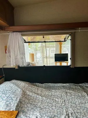 a bedroom with a bed and a window with a tv at Нереида in Sozopol