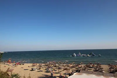 a beach with umbrellas and people in the water at Belle View - Menada Apartments in Sveti Vlas