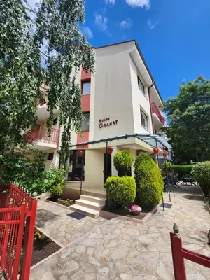 a building with a red fence in front of it at Guest House Granat in Sunny Beach