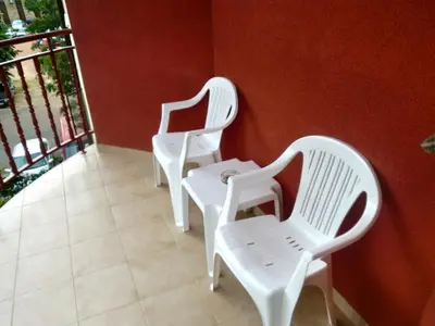 three white chairs sitting next to a red wall at Guest House Granat in Sunny Beach