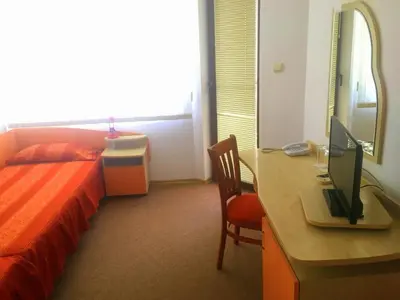 a bedroom with a bed and a desk with a computer at Guest House Granat in Sunny Beach