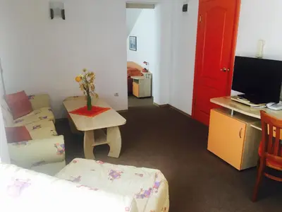 a living room with a couch and a table with a tv at Guest House Granat in Sunny Beach