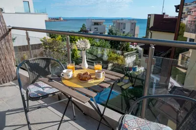 a table with food and drinks on a balcony at Via Sunride - Twin Maisonette Apartments by the sea in Sozopol