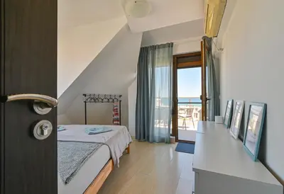 a bedroom with a bed and a large window at Via Sunride - Twin Maisonette Apartments by the sea in Sozopol
