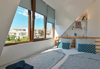 two beds in a room with two windows at Via Sunride - Twin Maisonette Apartments by the sea in Sozopol