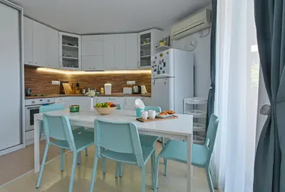 a kitchen with a white table and blue chairs at Via Sunride - Twin Maisonette Apartments by the sea in Sozopol