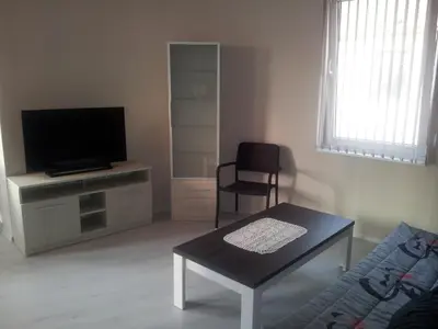 a living room with a tv and a table and a chair at Apartment Zlatina in Pomorie