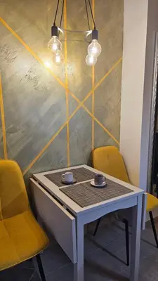 a table with two cups and two yellow chairs at Vladan apartments in Sozopol