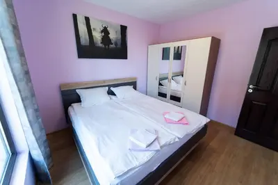 a bedroom with a bed with white sheets and pink walls at GGeorgi Sarafovo in Burgas City