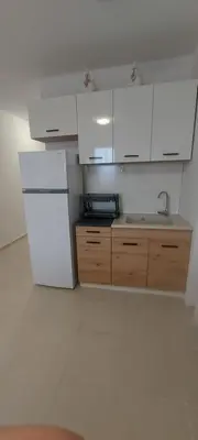 a kitchen with a white refrigerator and wooden cabinets at Condo Santosha on the beach in Pomorie