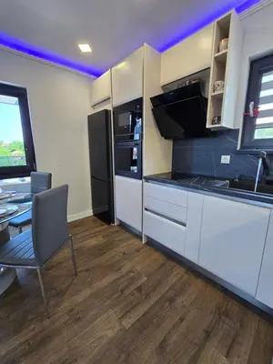 a kitchen with white cabinets and a table and a refrigerator at Къща Холидей Обзор in Obzor
