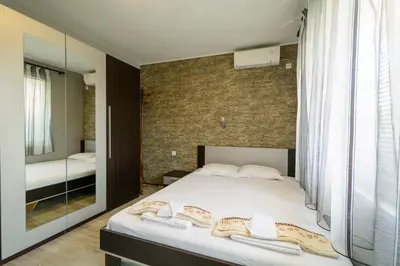 a bedroom with a large bed and a mirror at Apartment Yanevi in Lozenets